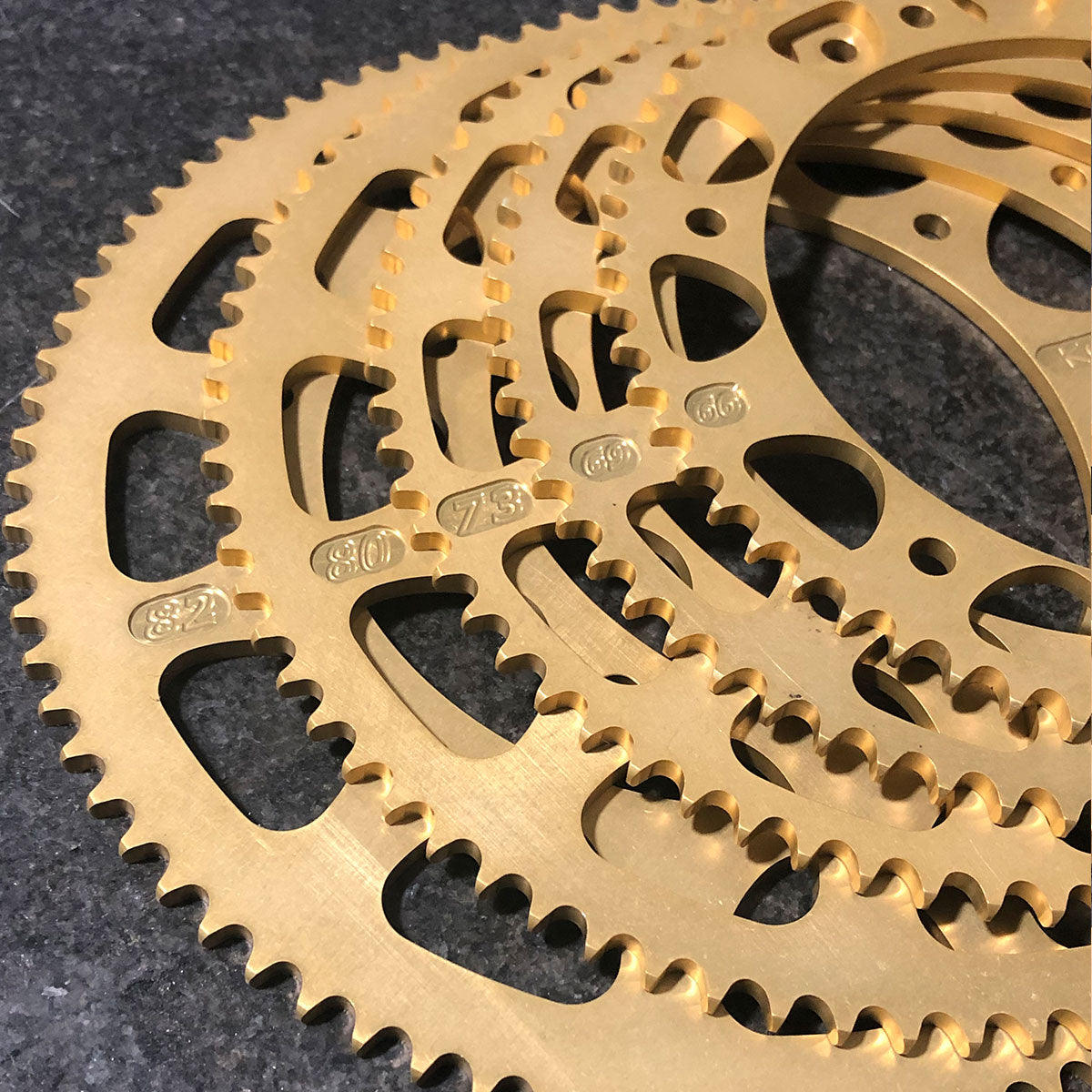 Several gold Kodiak 219 kart sprockets showing different tooth counts